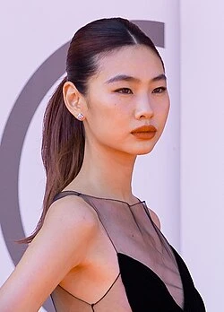 Jung Ho-yeon wearing luminous spring outfits with juicy warm hues, showcasing papaya orange, sunny marigold, aqua turquoise, creamy ivory, and rose gold from the Warm Spring palette.